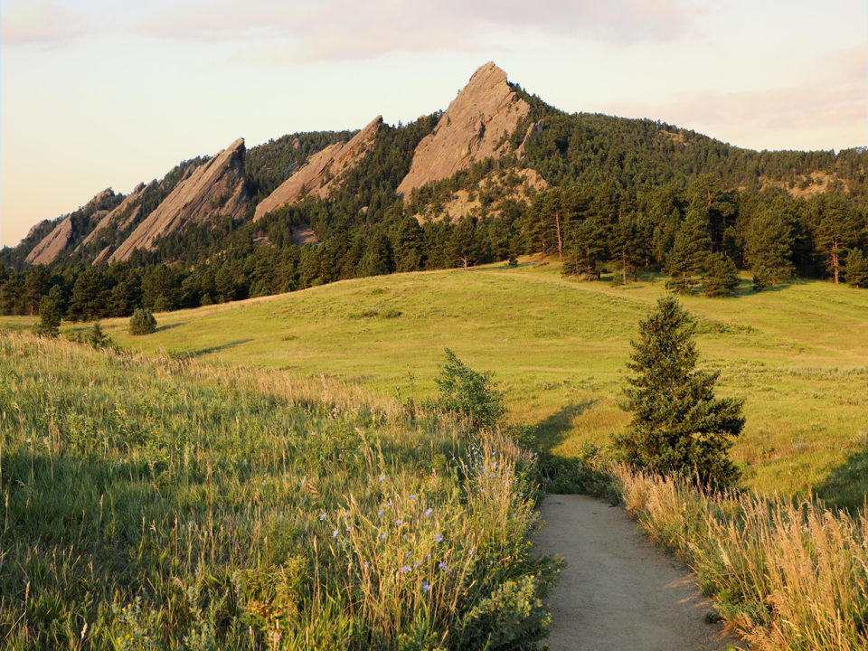 Boulder's iconic Flatirons sentinel over Chautauqua's greenery.