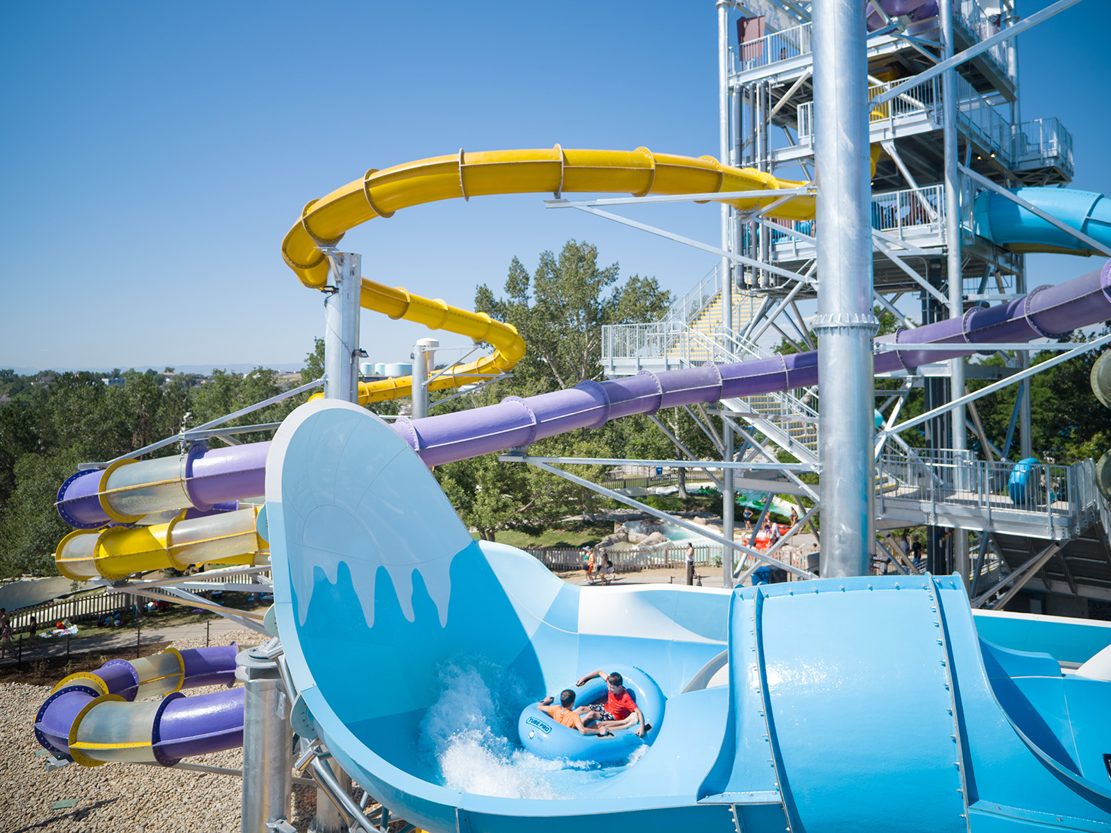 Two people ride down a blue waterslide