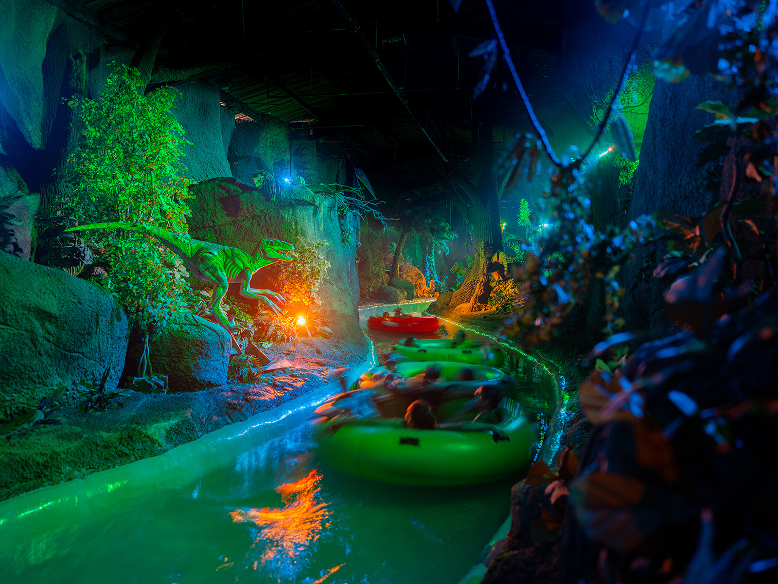 People float past animatronic dinosaurs on a water ride