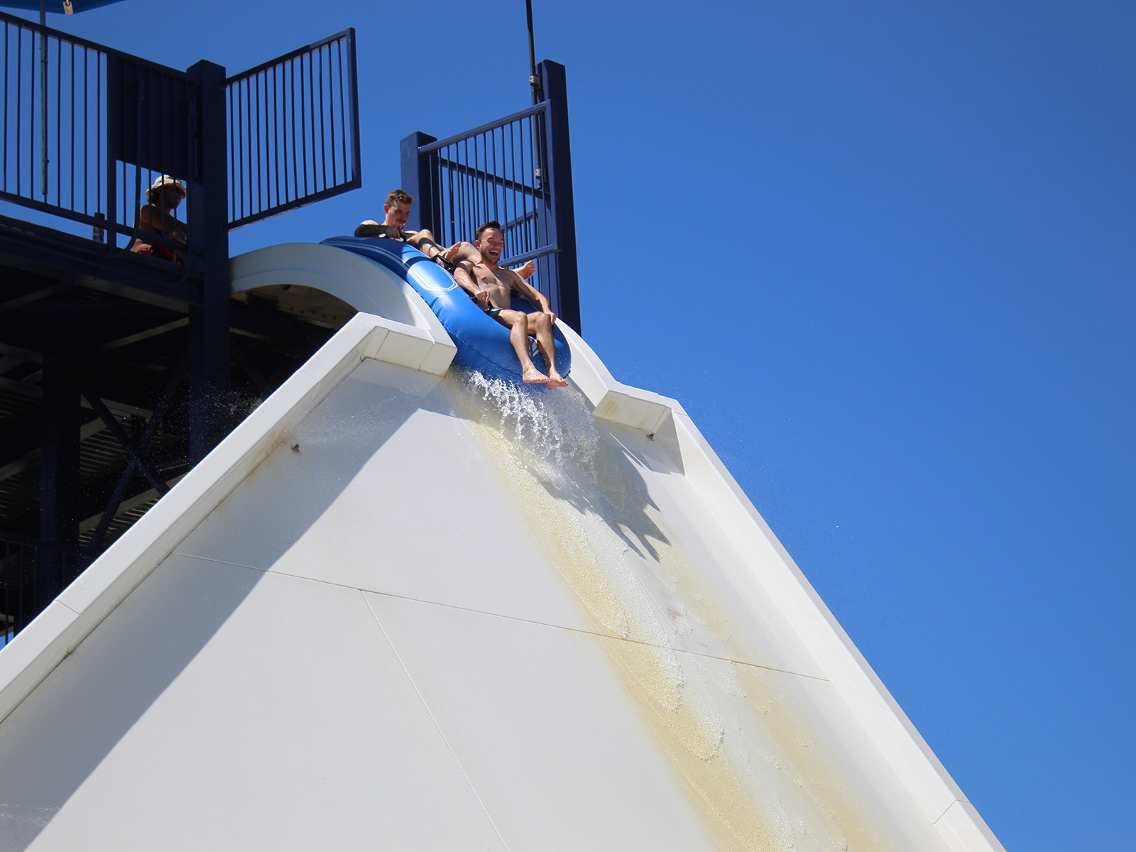 Two people in a tube sit at the edge of a waterslide