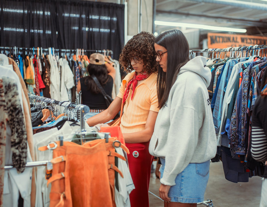 People search through racks of clothes at Thrift Con
