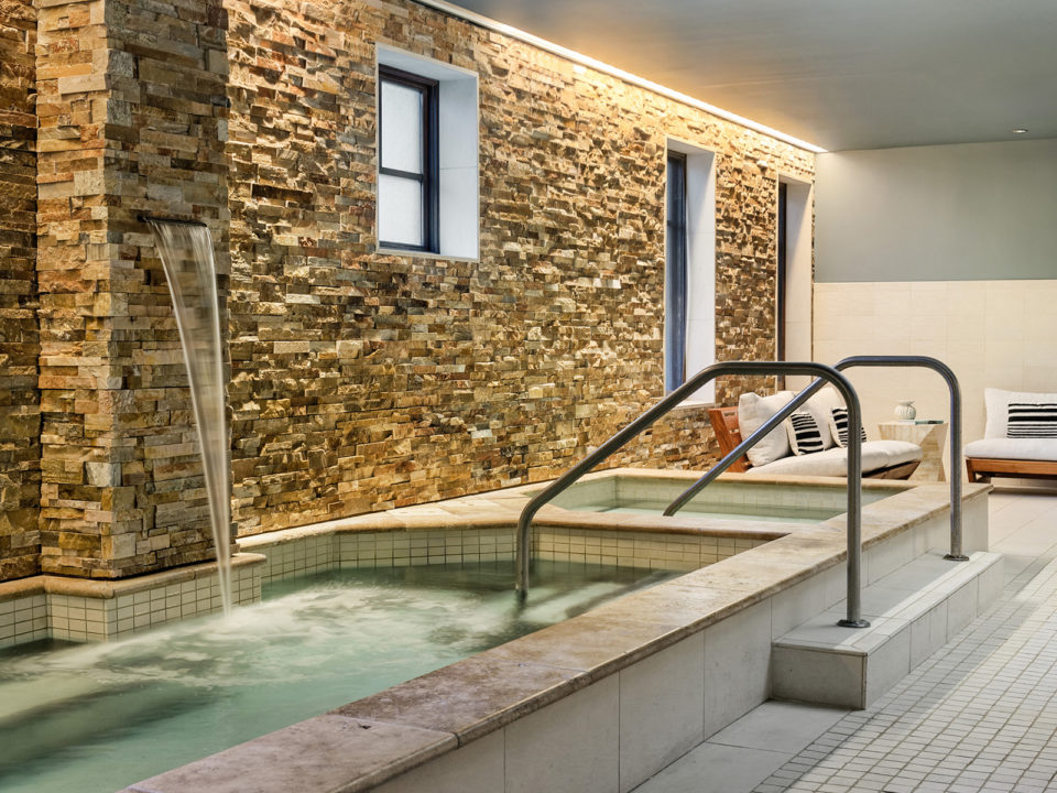 waterfall cascades into an indoor pool and hot tub