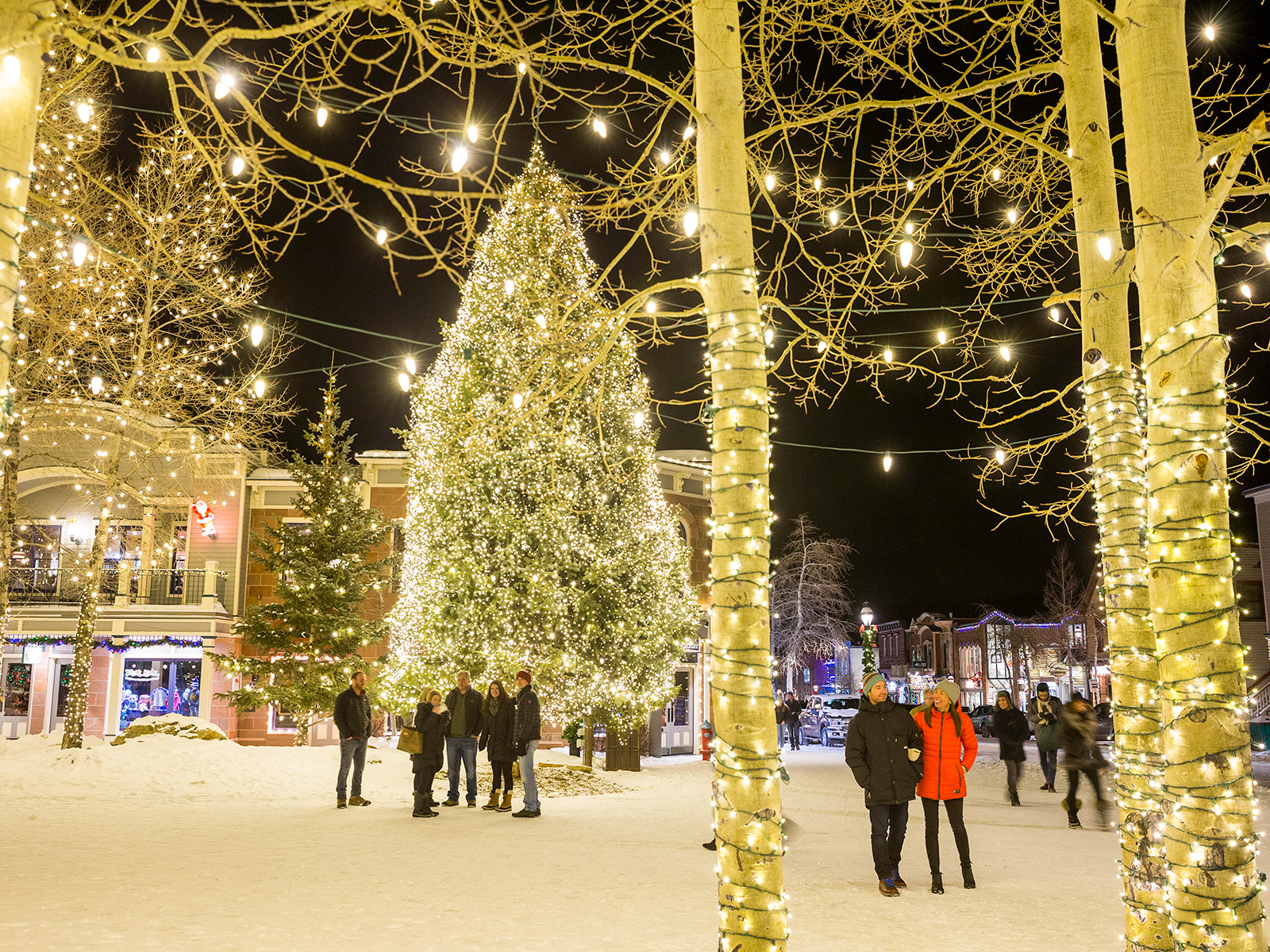 People walk in a square lit up my Christmas lights