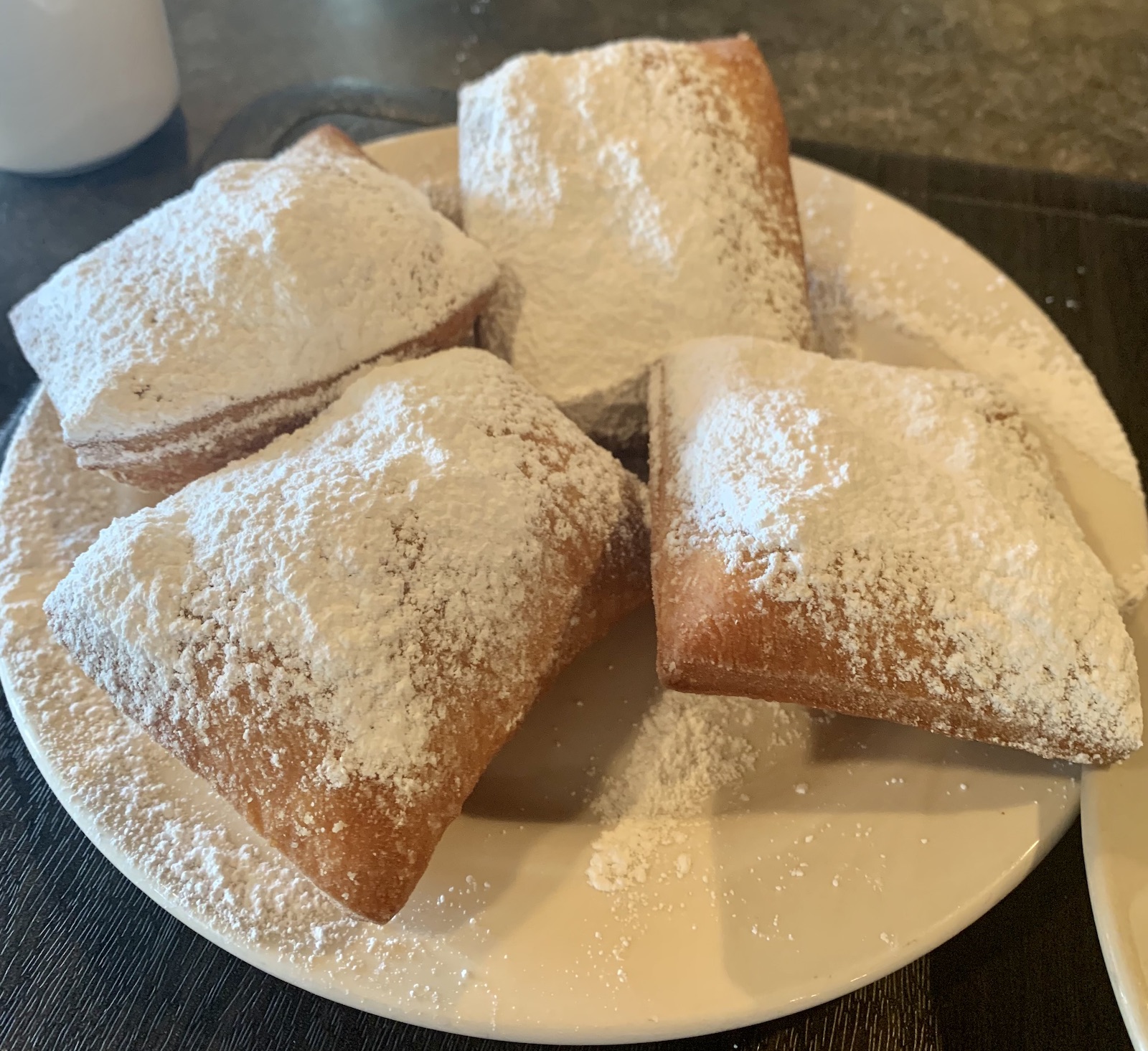 A plate of four beignets covered with powdered sugar at Lucile's Creole Cafe.