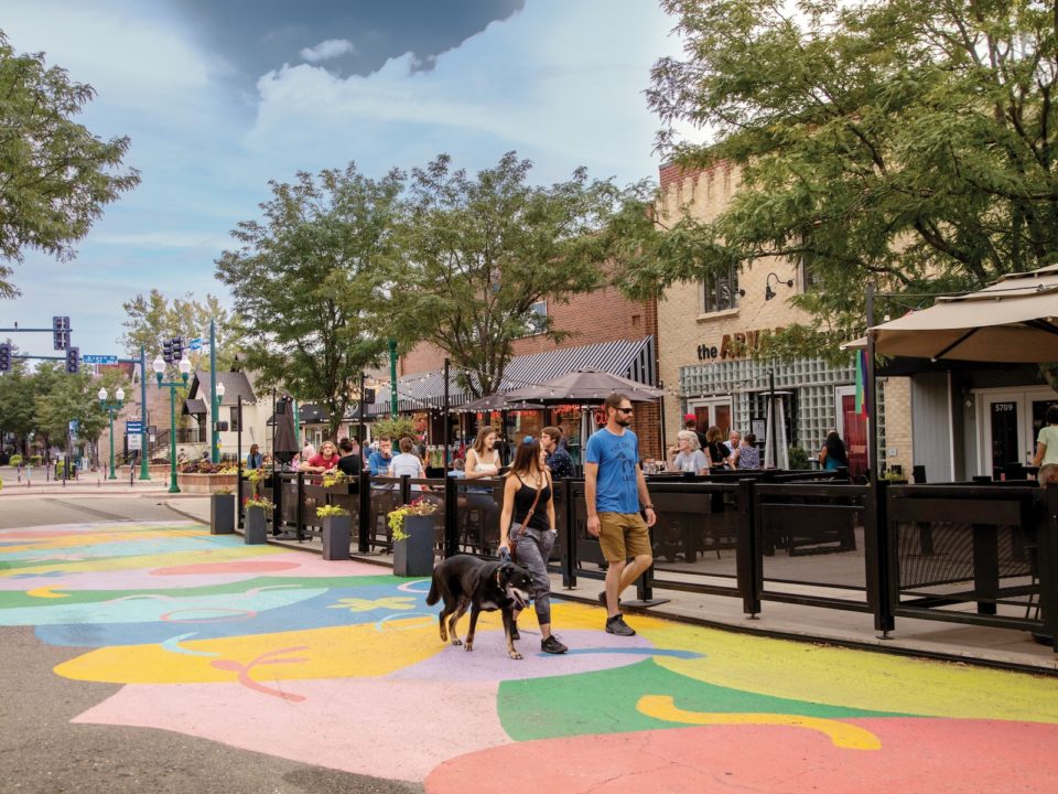 Two people and a dog walk through Olde Town Arvada