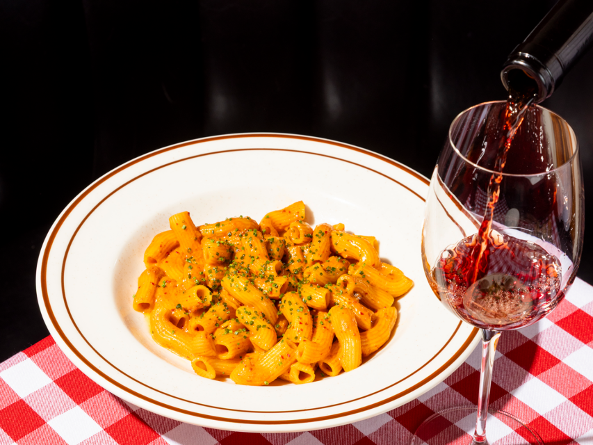 spicy rigatoni alla vodka in a bowl with a glass of red wine