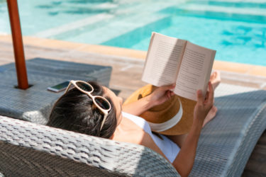 A woman lies on a sun bed reading a book
