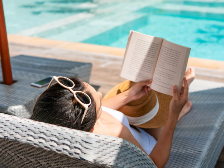 A woman lies on a sun bed reading a book