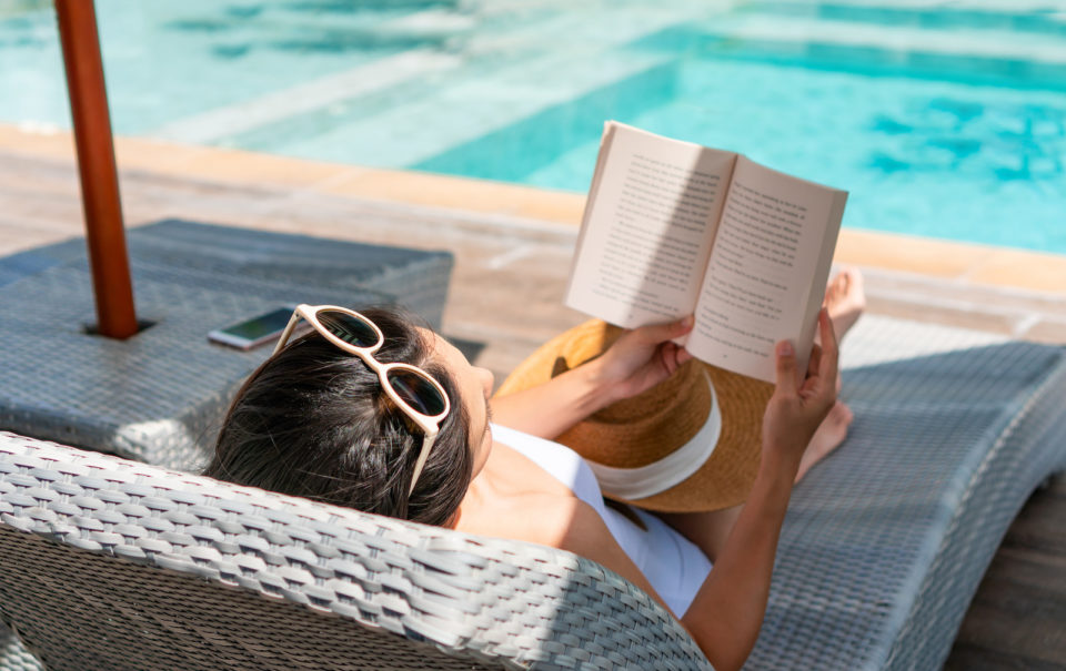 A woman lies on a sun bed reading a book