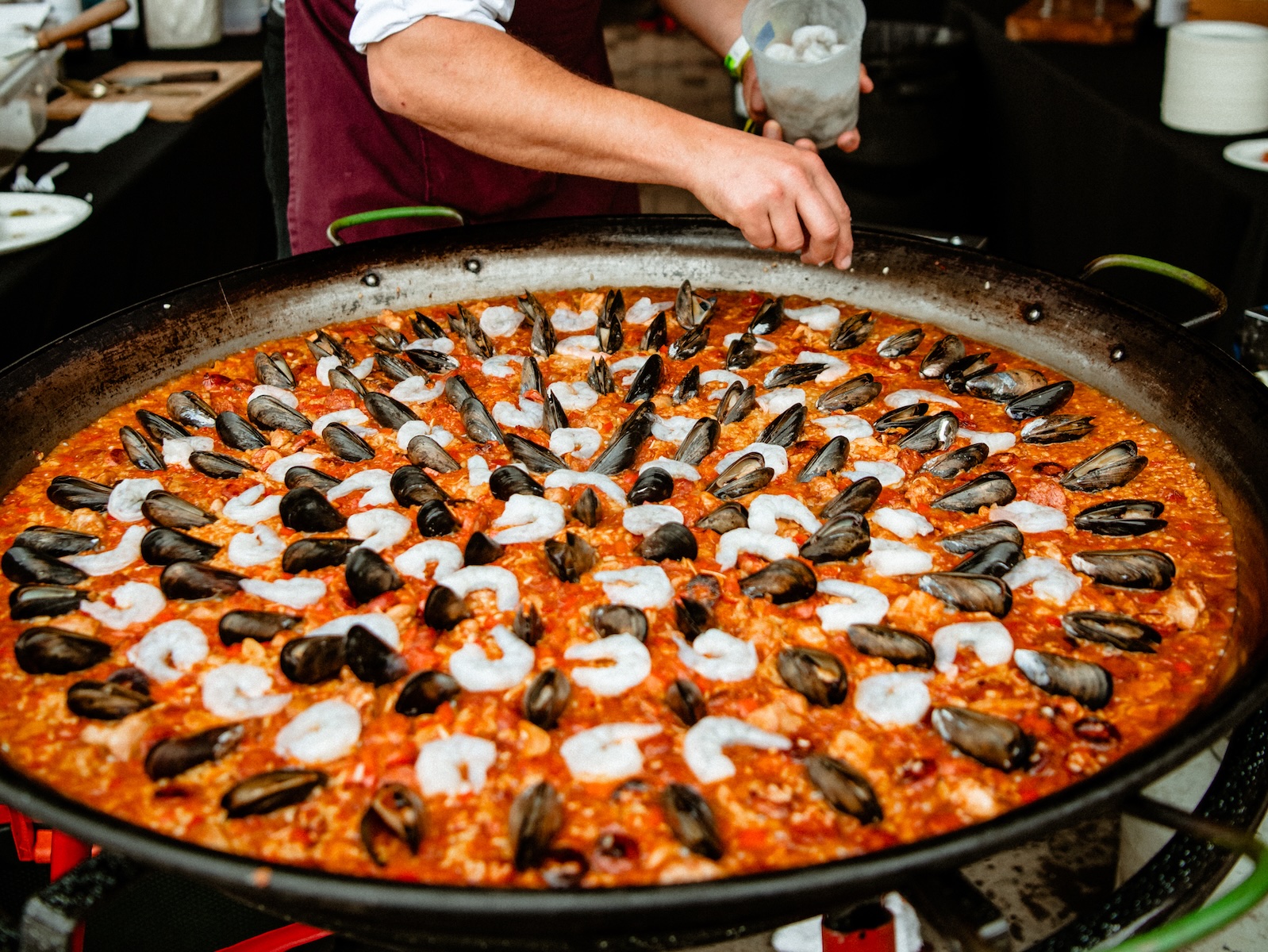 A large pan of paella being topped with mussels and shrimp