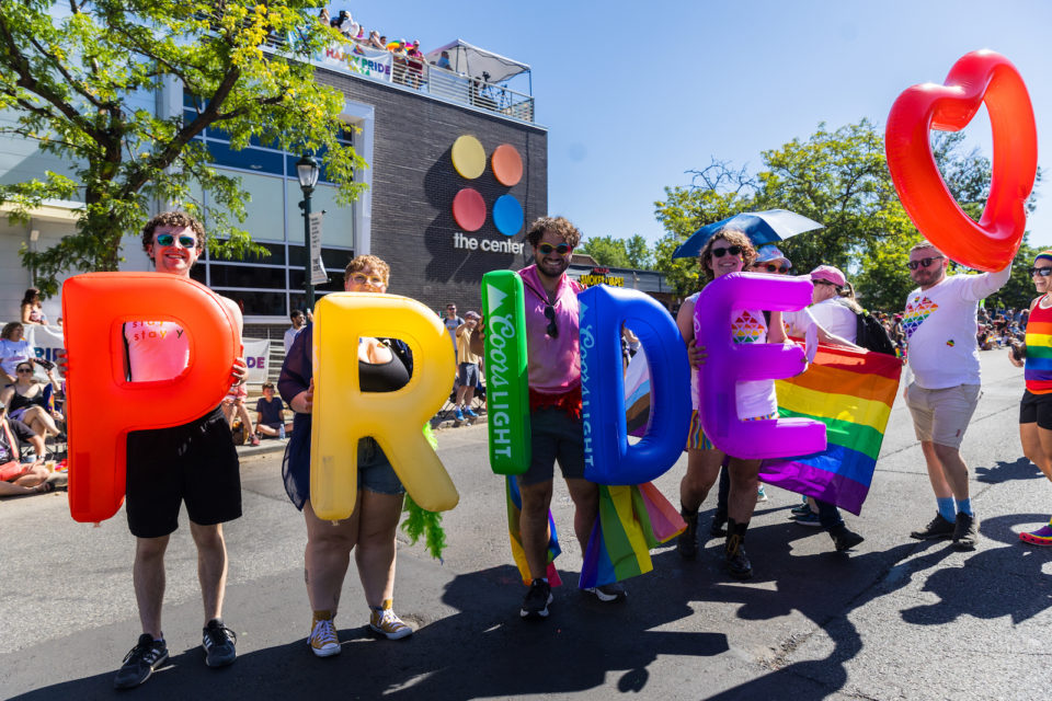 People hold letter balloons that spell the word "PRIDE"