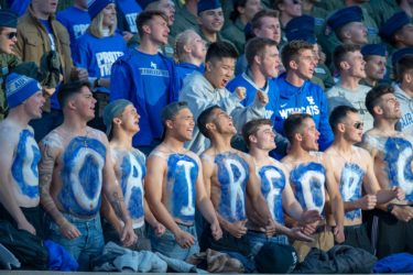 Shirtless fans with Go Air Force painted on their chests in blue and white