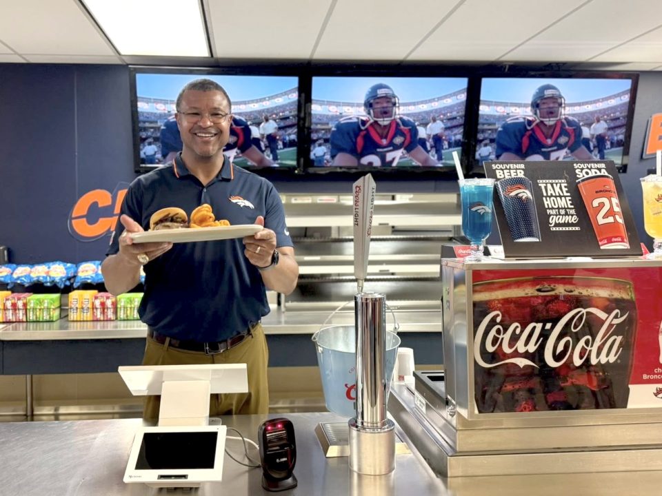 Denver Broncos alumni Steve Atwater holding a tray with a cheeseburger at his Atwater Grill food counter