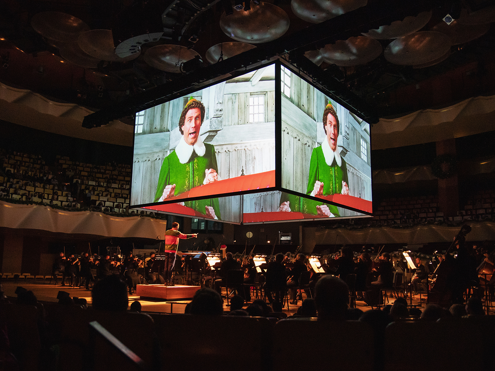 Elf on a big screen above an orchestra