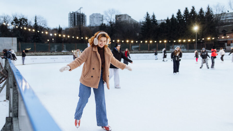 A joyful woman glides gracefully across the ice rink, enjoying the winter wonderland