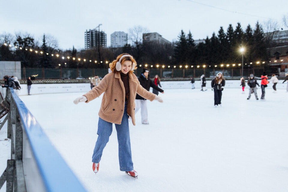 A joyful woman glides gracefully across the ice rink, enjoying the winter wonderland