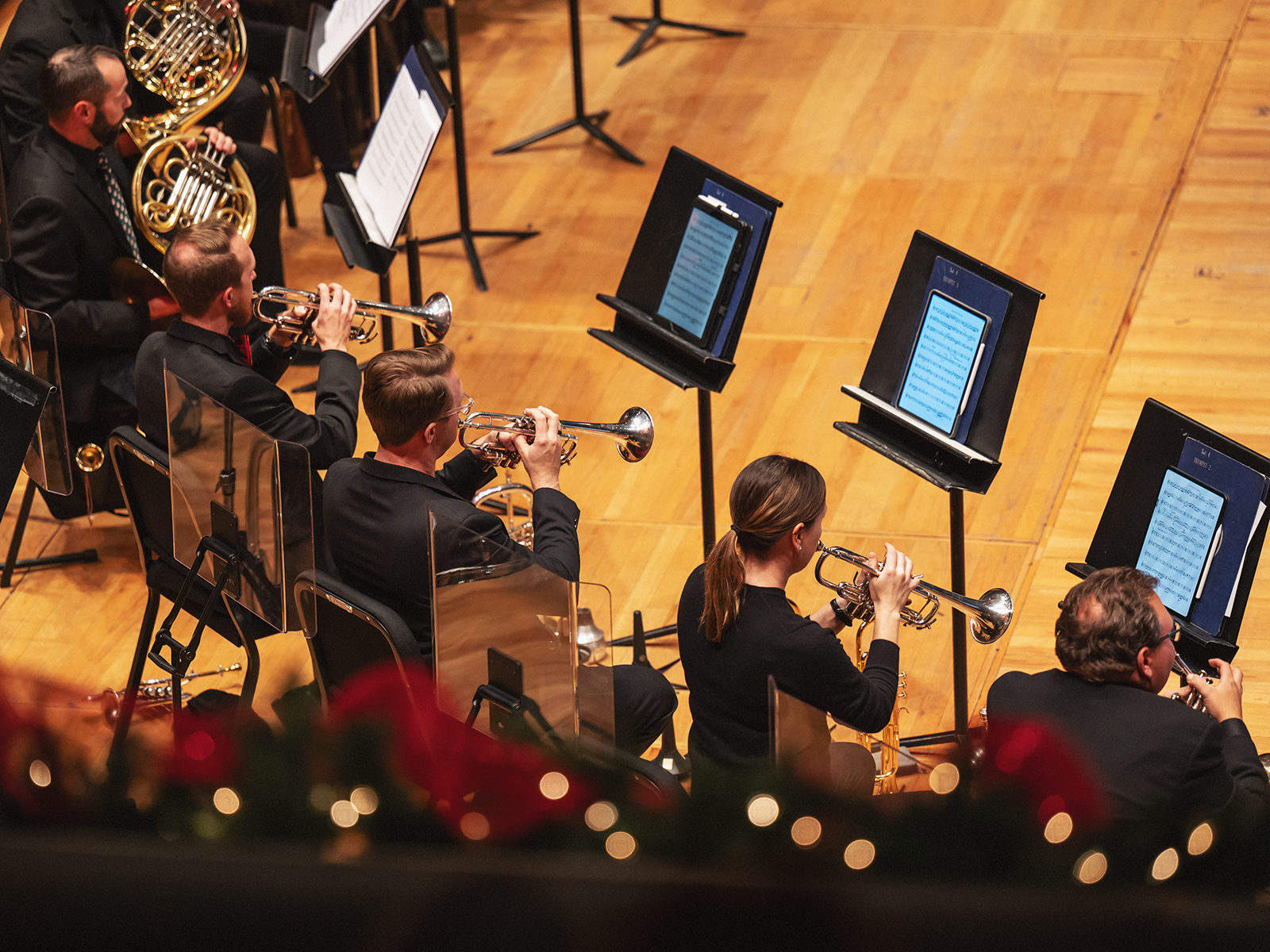 Musicians in front of music stands on a holiday-themed stage