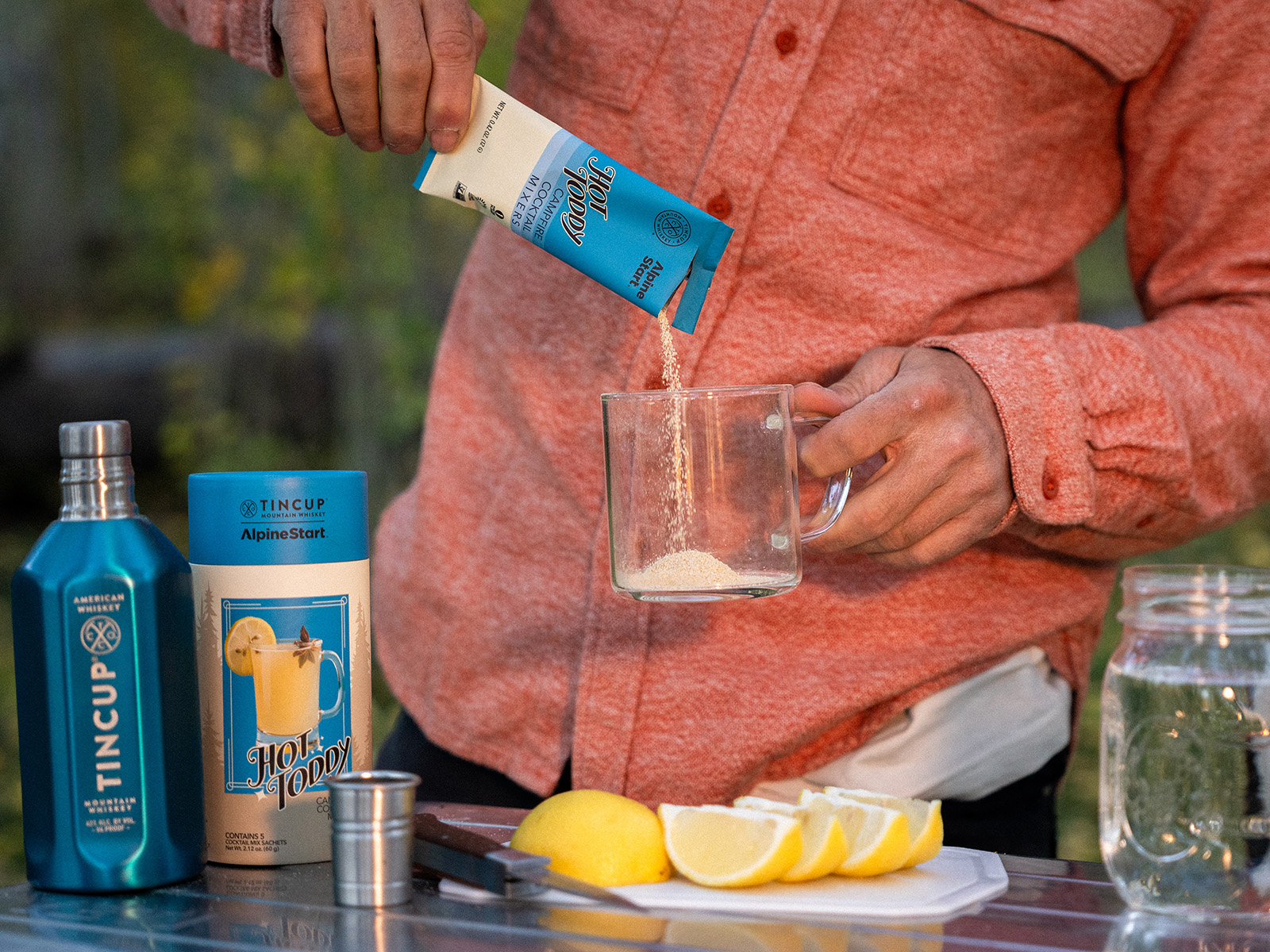Hand pours a cocktail powder into a clear mug