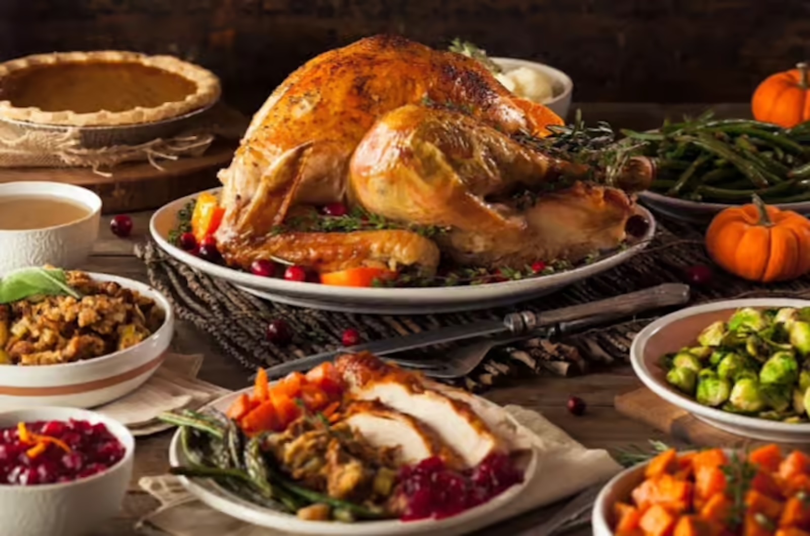 A roast turkey on an oval platter with a plate of Thanksgiving foods and several side dishes