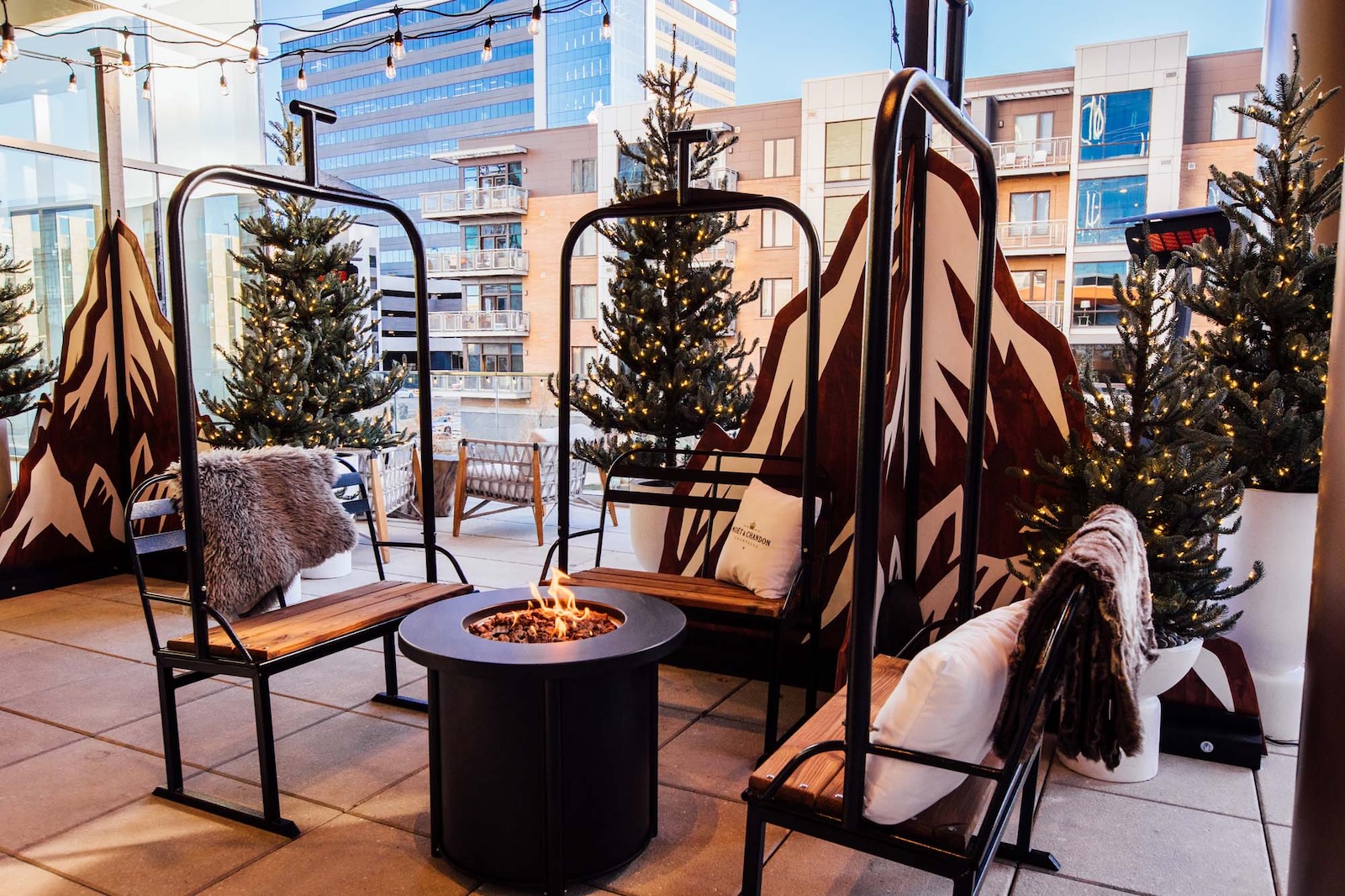 A winter bar with a fire pit and seating built to resemble ski lift chairs