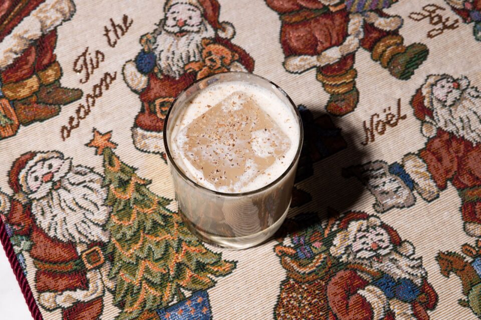 A creamy cocktail on ice in a rocks glass with Santa Claus fabric underneath