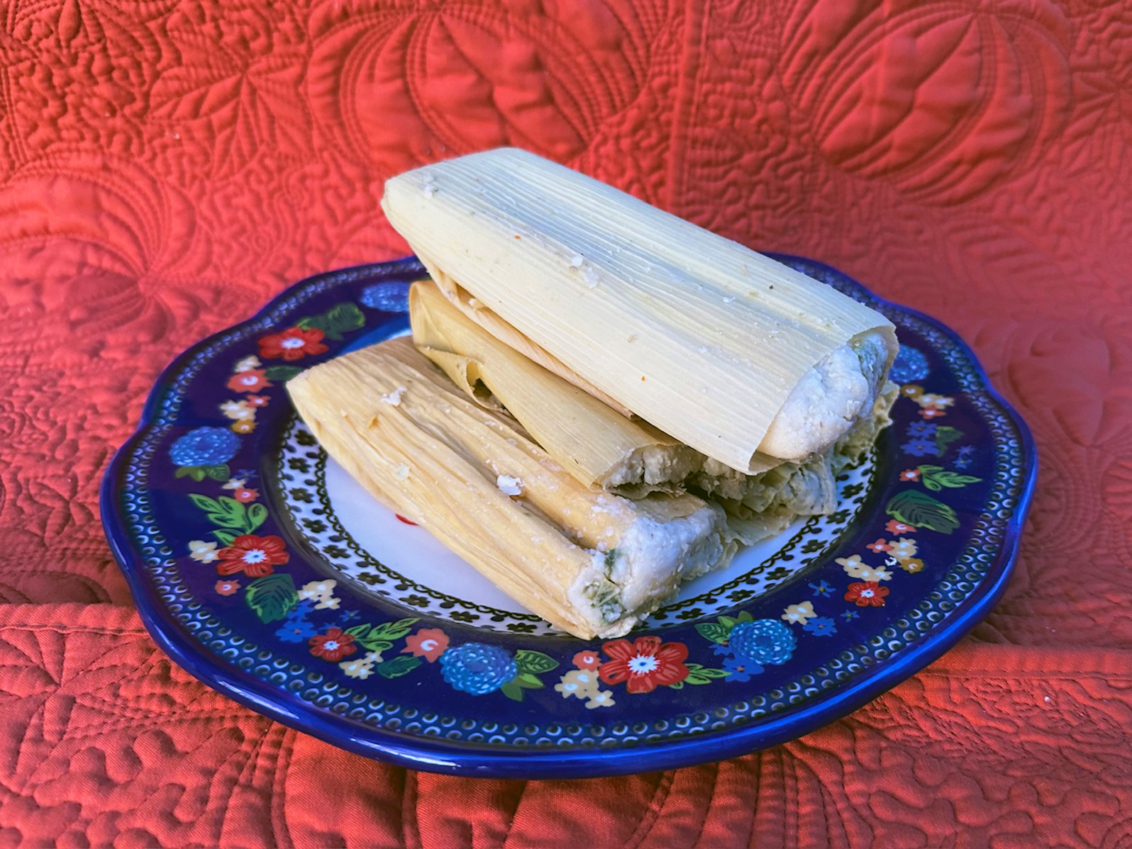 A plate of tamales on a festive blue plate