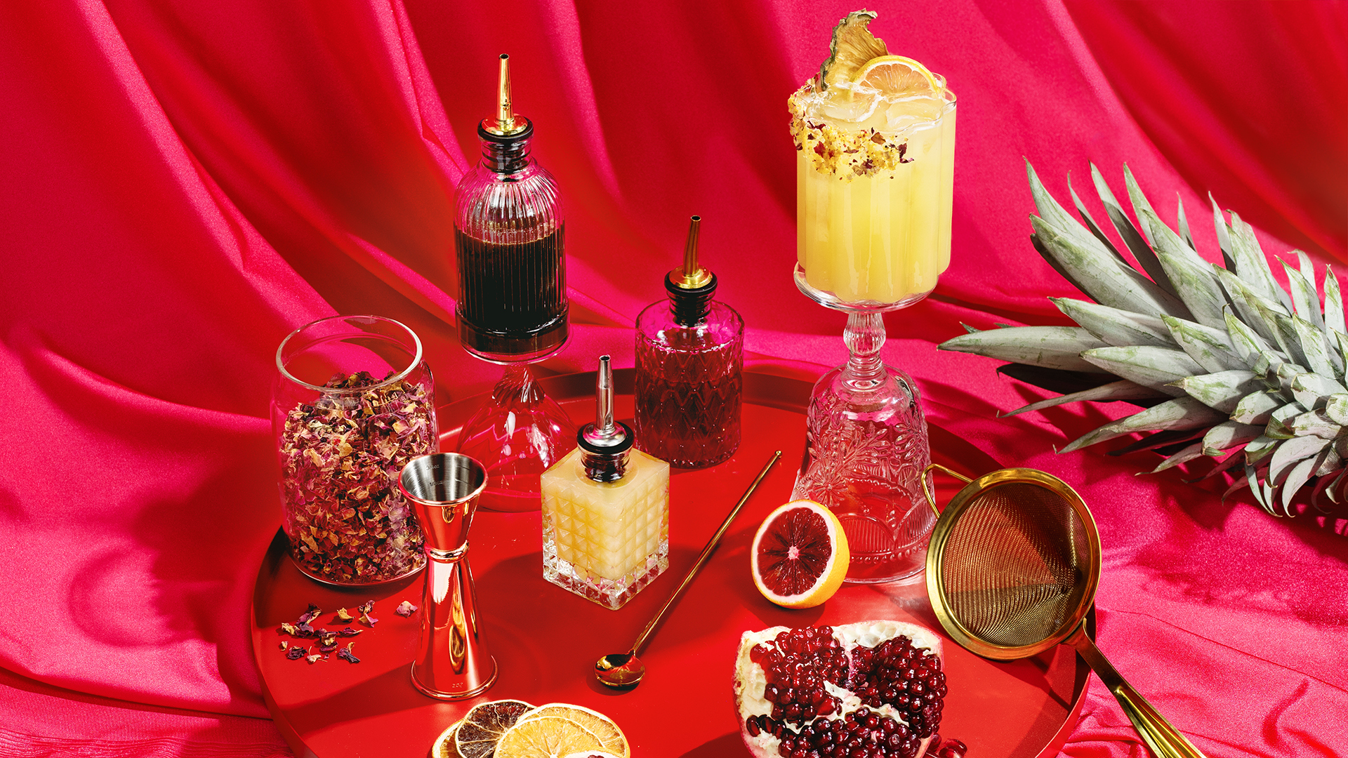 Mocktail ingredients on a red tray on magenta fabric