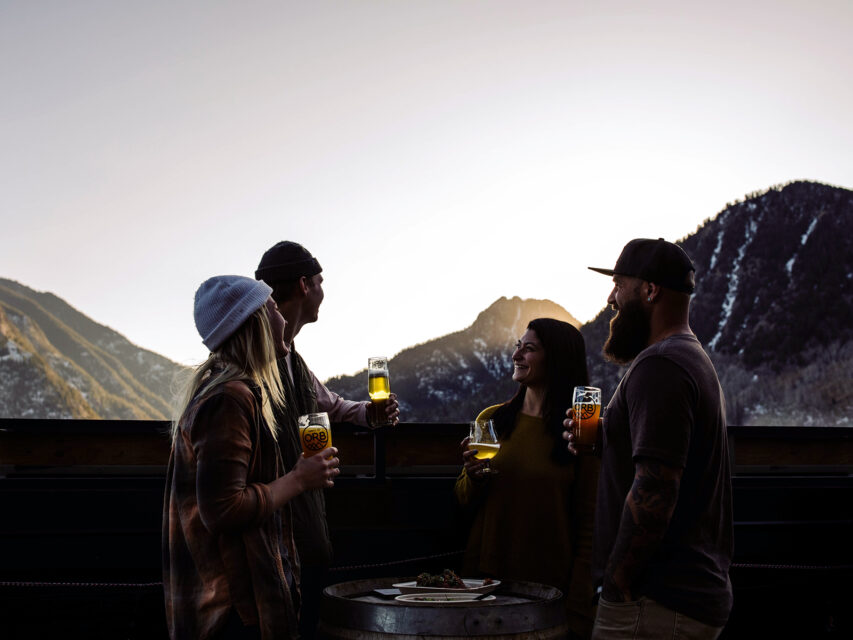 Four people enjoying après at Outer Range Brewing off I-70