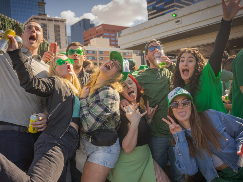 Young adults dressed in green and drinking beer