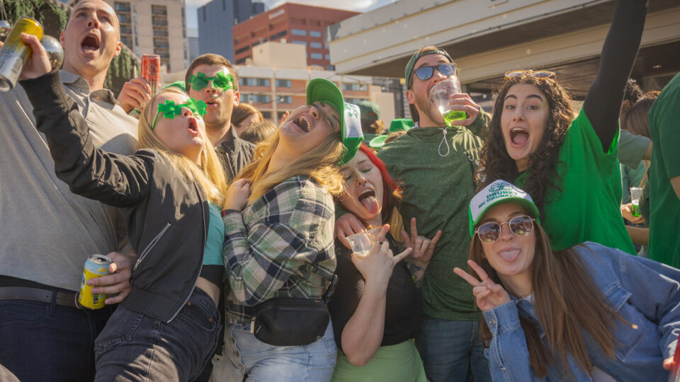 Young adults dressed in green and drinking beer