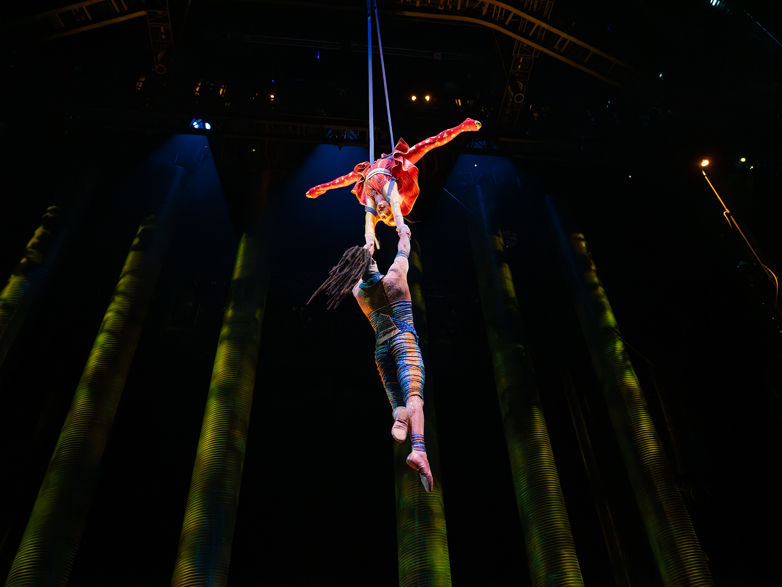Two aerial performers hang from the ceiling