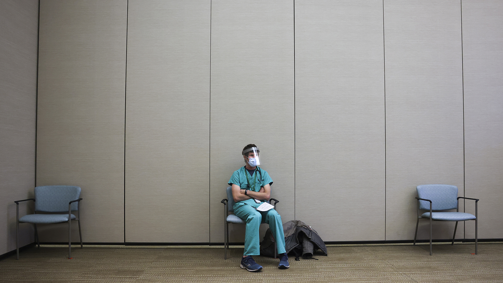 A person wears scrubs and a mask while social distancing
