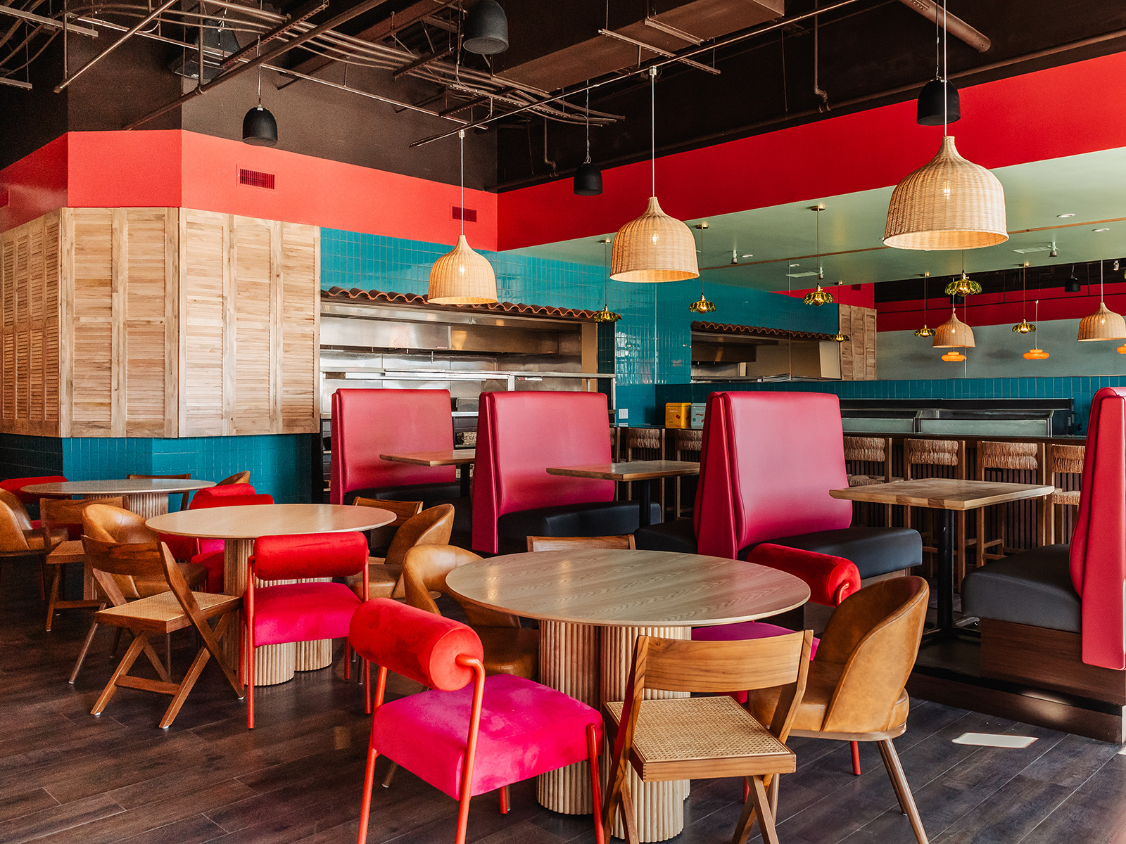 Restaurant dining room with rattan pendant lights, blue tiles, and hot pink booths