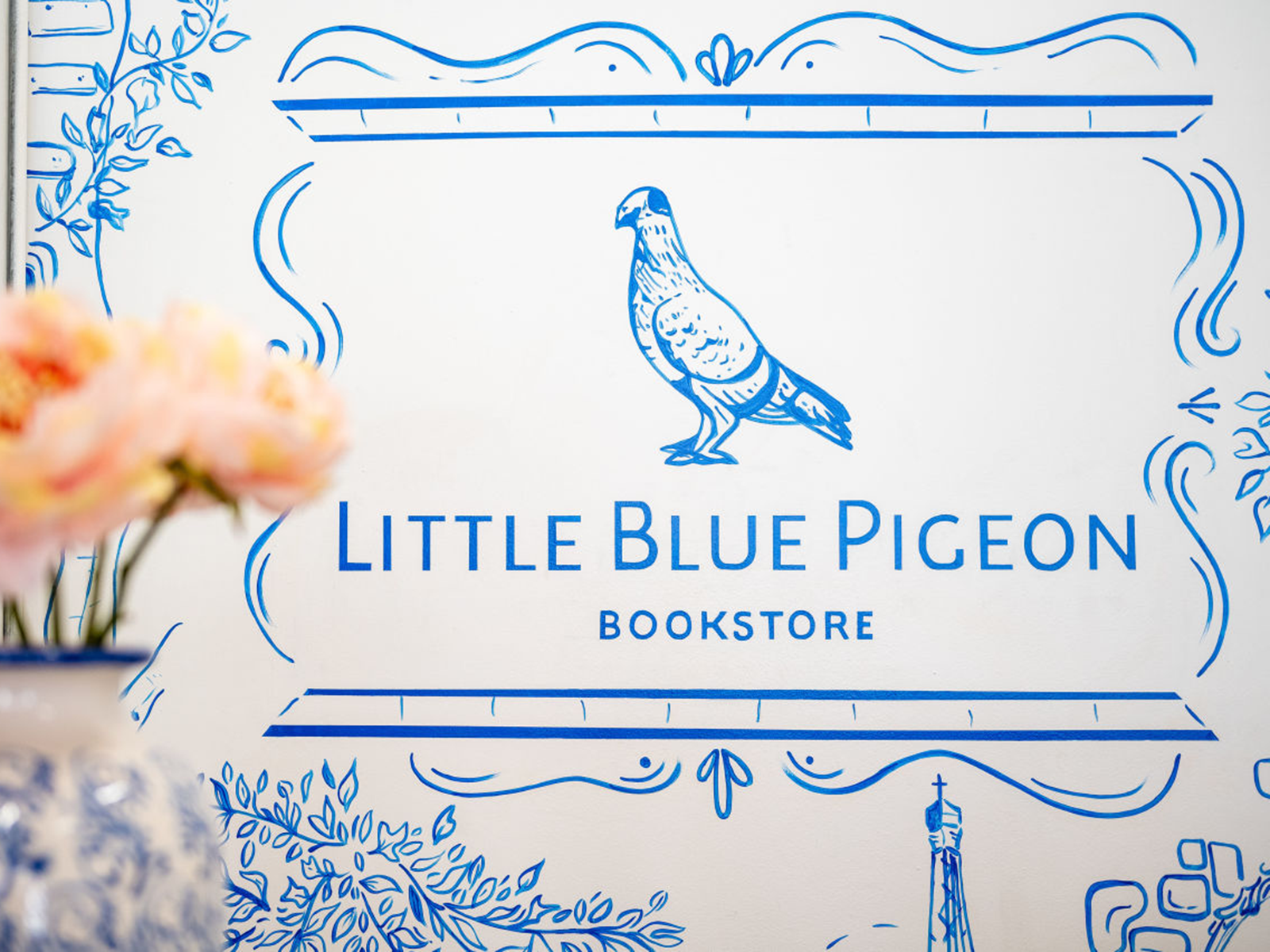 White and blue mural that reads "Little Blue Pigeon Bookstore"