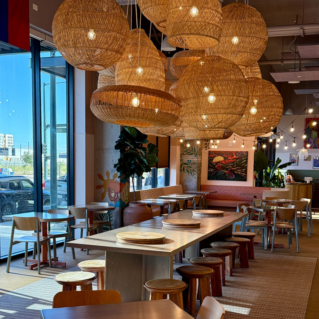 A cloud of woven pendant lights hangs over a table