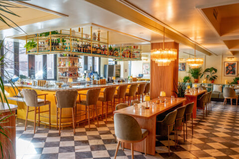 Bar with checkered floors, velvet scalloped bar stools, and chandeliers