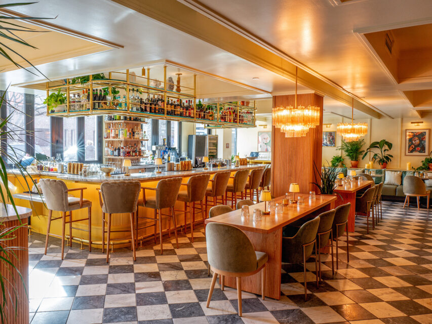 Bar with checkered floors, velvet scalloped bar stools, and chandeliers