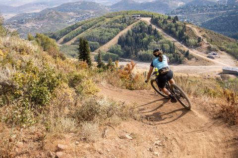 Woman rides down a mountain biking trail in Park City, Utah