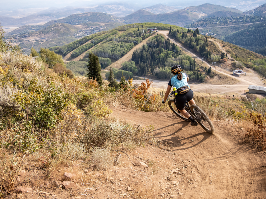 Woman rides down a mountain biking trail in Park City, Utah