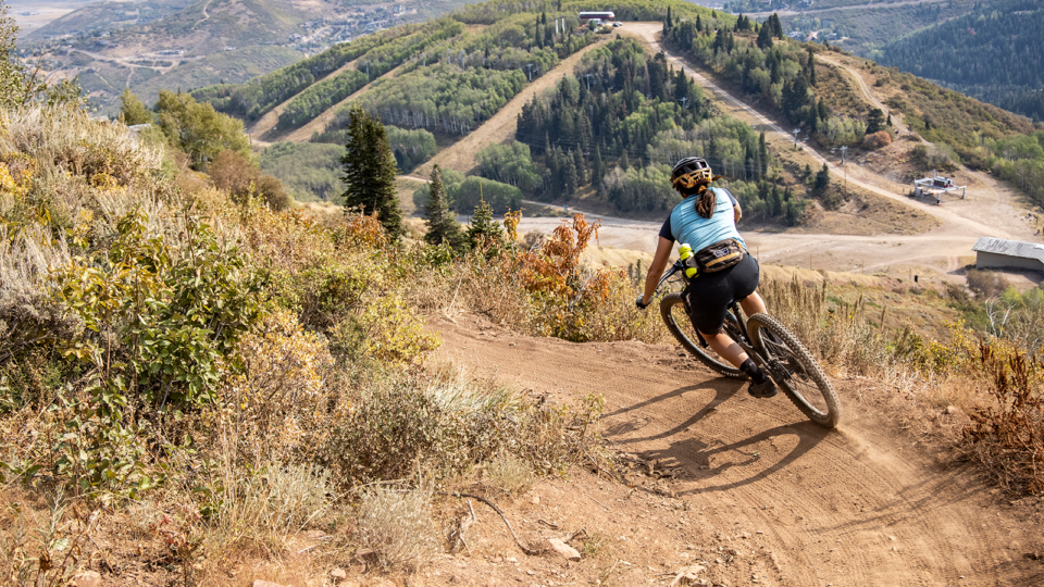 Woman rides down a mountain biking trail in Park City, Utah