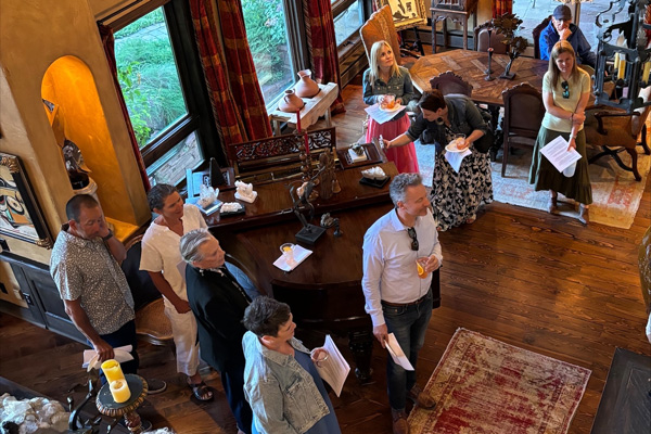 People standing around in a home's living room looking at art