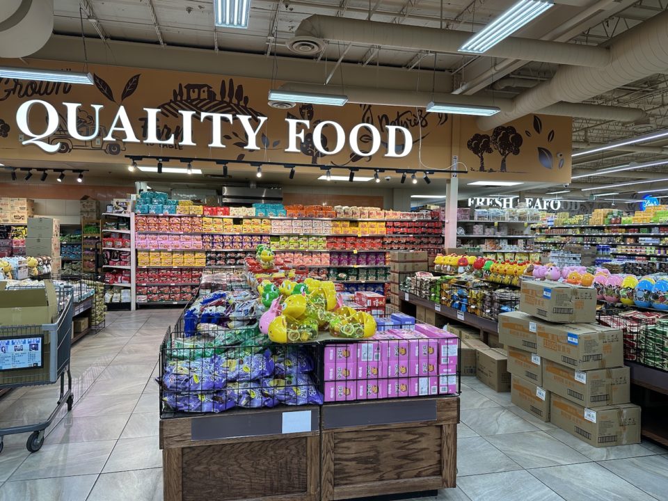 The interior of GW Supermarket with a sign reading "Quality Food" above aisles of dry goods