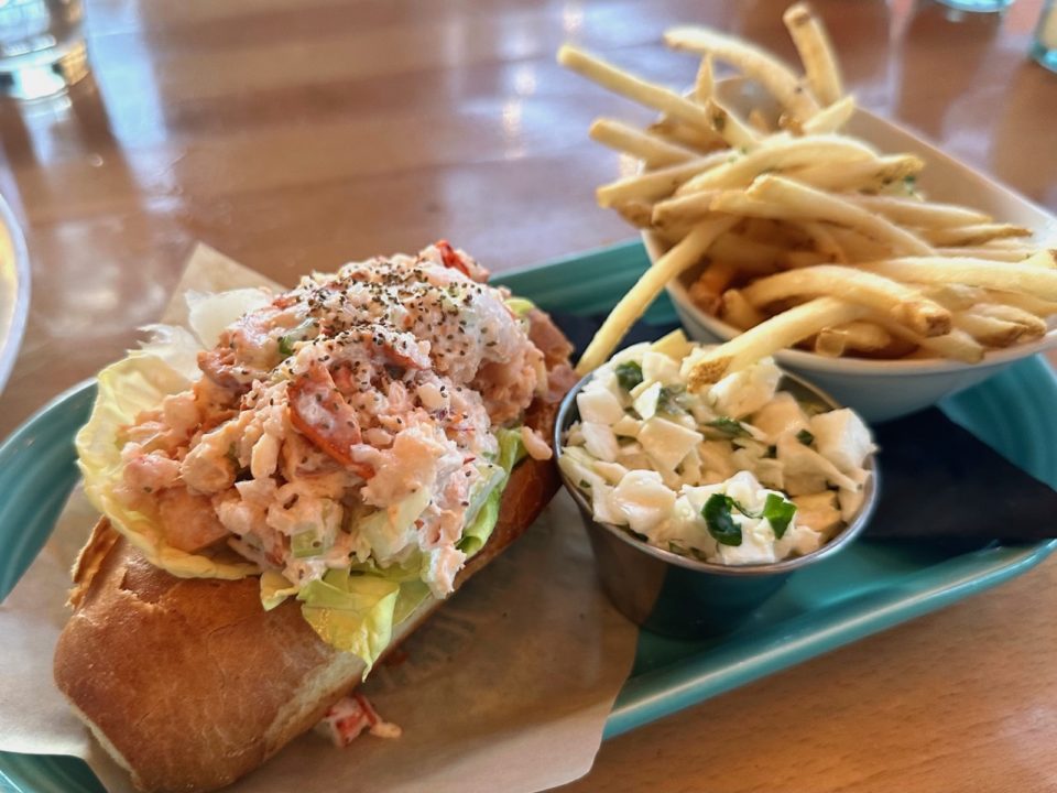 A lobster roll with French fries and cole slaw