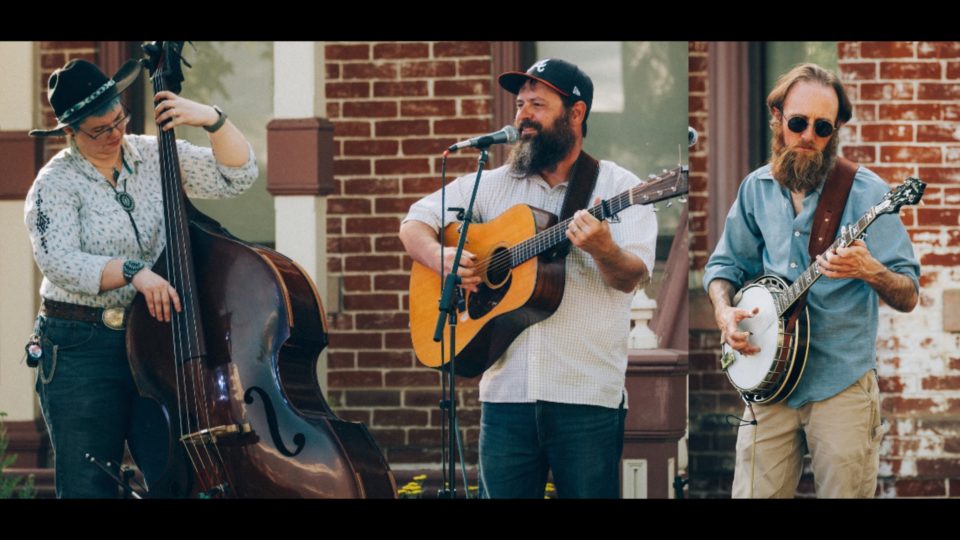 A musical band of three people outside playing music.