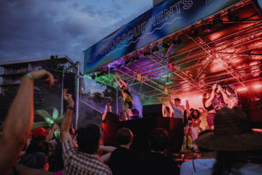 Crowd dances to a band on stage at dusk