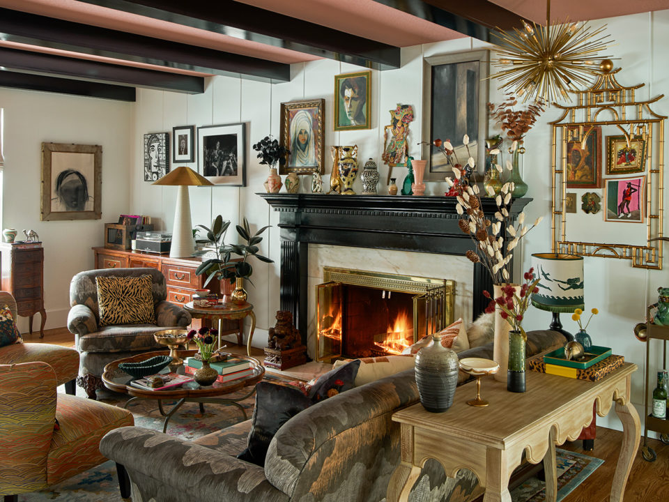 Living room filled with art, table decor, throw pillows, and a black fireplace