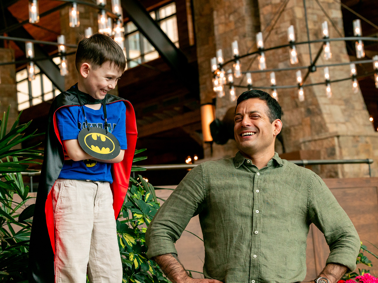 Son dressed in a superman costume smiles at his dad