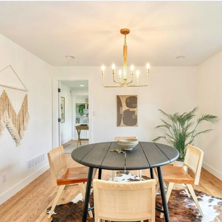 White dining room with a black table and rattan chairs