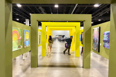 Two people walk through yellow arches in an art exhibit