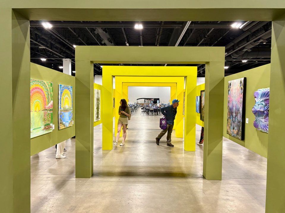 Two people walk through yellow arches in an art exhibit